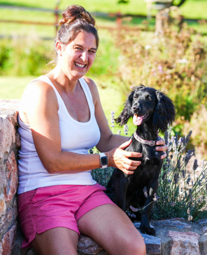 Fiona sitting outdoors with her black spaniel